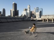 Mann auf dem Dach einer Stadt liest. — Stockfoto