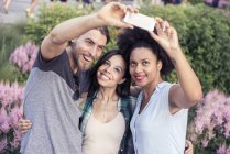 Mujeres y un hombre posando para una selfie - foto de stock