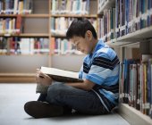 Хлопчик у бібліотеці читає книгу . — стокове фото