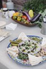 Tigela de verduras, mergulhos e pão em uma mesa — Fotografia de Stock