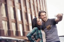 Hombre y mujer tomando un selfie en la ciudad - foto de stock