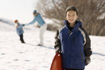 Хлопчик тримає санки в снігу — стокове фото