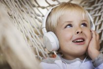 Хлопчик лежить в гамаку з музичними навушниками — стокове фото