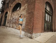 Donna che corre lungo una strada urbana — Foto stock