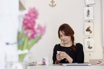 Mujer sentada en el escritorio haciendo llamada en el teléfono inteligente - foto de stock