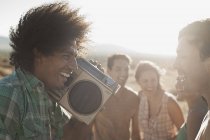 Friends walking on the open road with a boombox. — Stock Photo
