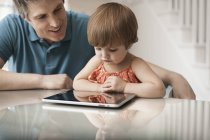 Батько і дочка дивляться на цифровий планшет — стокове фото