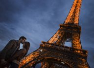 Pareja de pie bajo la Torre Eiffel - foto de stock