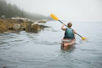 Homme pagayant un kayak sur l'eau calme — Photo de stock