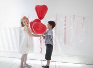 Niño y niña sosteniendo globos . - foto de stock