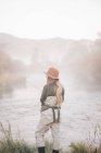 Pescatrice in piedi sulle rive di un fiume — Foto stock