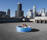 Couple in inflatable pool on rooftop — Stock Photo
