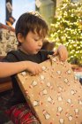Мальчик разворачивает большой подарок — стоковое фото