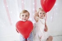 Jeune garçon et fille tenant des ballons . — Photo de stock