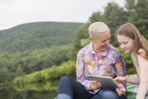 Mujer y niña usando una tableta digital - foto de stock