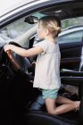 Девушка на коленях на водительском сиденье автомобиля — стоковое фото