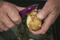 Homme épluchant une pomme de terre — Photo de stock