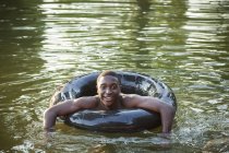 Man floating with tyre swim float. — Stock Photo