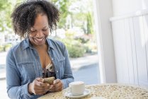 Жінка тримає смартфон у кав'ярні — стокове фото