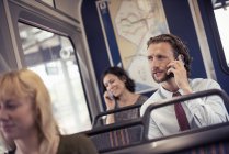Люди в автобусі, двоє розмовляють на мобільних телефонах — стокове фото