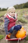 Girl sitting on top of harvested pumpkins. — Stock Photo