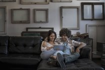 Пара на дивані, дивиться на цифровий планшетний. — стокове фото