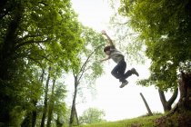 Boy leaping from wood — Stock Photo
