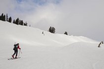 Esquiador peles até uma encosta de neve — Fotografia de Stock
