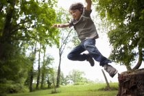 Boy leaping from wood — Stock Photo