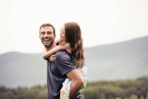 Man giving child a piggyback in a meadow. — Stock Photo