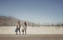 Couple carrying suitcases by the roadside — Stock Photo