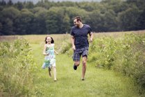 Man and  child running through meadow — Stock Photo