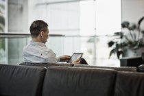 Человек сидит с помощью цифрового планшета — стоковое фото