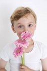 Молодий хлопчик тримає купу квітів . — стокове фото