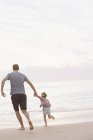 Man playing on a sandy beach with daughter — Stock Photo