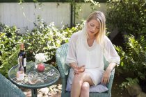 Femme blonde assise dans un jardin en été — Photo de stock