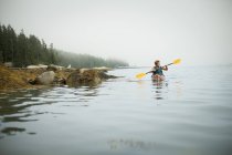 Homem remando um caiaque em água calma — Fotografia de Stock