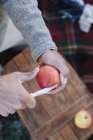 Homme coupe pomme avec un couteau tranchant . — Photo de stock