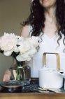 Frau trägt Tablett mit Teekanne und Blumen — Stockfoto