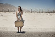 Frau mit Koffer am Rande der Autobahn. — Stockfoto