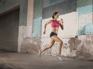 Mulher correndo ao longo de uma rua urbana — Fotografia de Stock