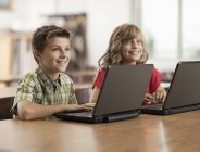 Dos niños usando una computadora portátil - foto de stock