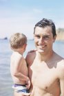 Homme portant son fils sur la plage — Photo de stock