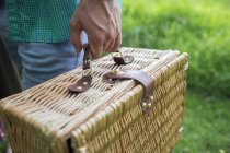 Hand holding a wicker picnic basket. — Stock Photo