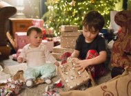 Children sitting among presents by tree — Stock Photo