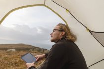 Man in tent holding a digital tablet — Stock Photo