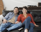 Couple assis sur un canapé et regarder la télévision . — Photo de stock