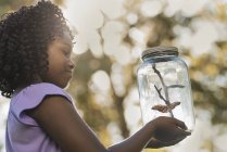 Девушка держит стеклянную банку с бабочкой — стоковое фото
