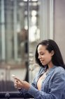 Жінка перевіряє мобільний телефон на міській вулиці — стокове фото