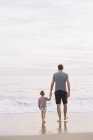 Man with daughter on beach by the ocean — Stock Photo